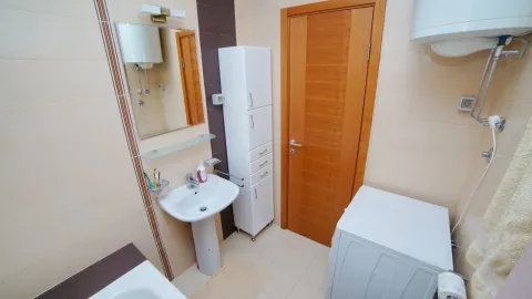 Pregledno kupatilo sa umivaonikom, ormarićem, drvenim vratima i veš mašinom. - image 6