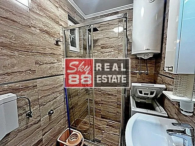 Bathroom with a shower cabin, washbasin, and water heater.