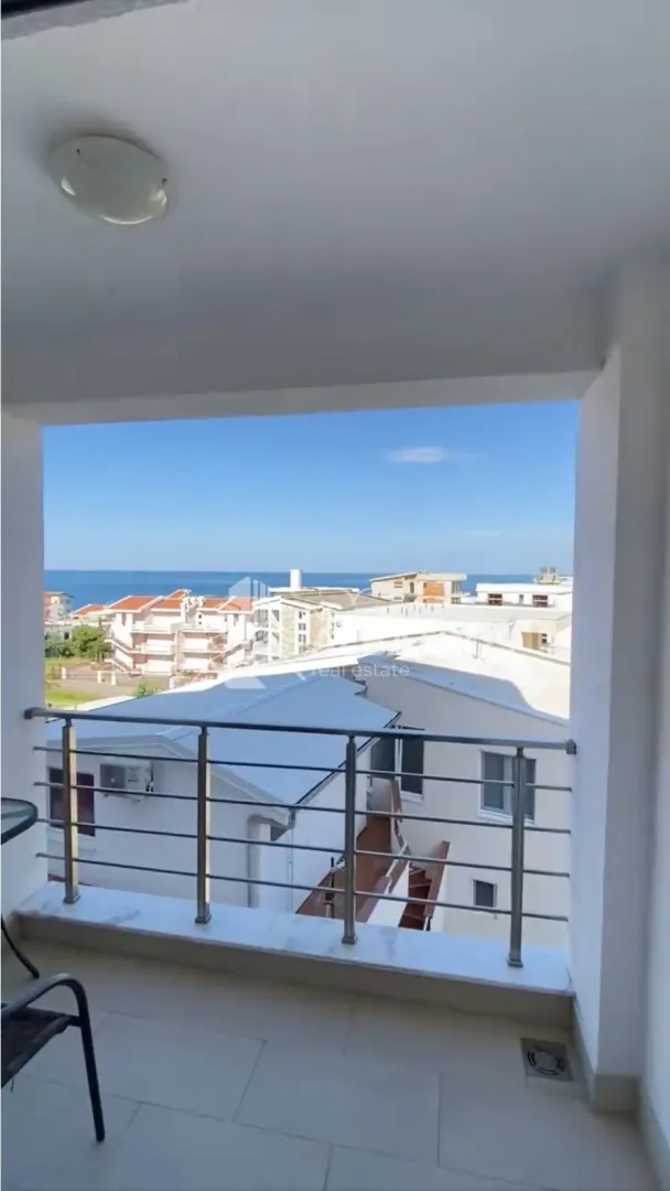 Natkriveni balkon sa pogledom na more i okolne zgrade.