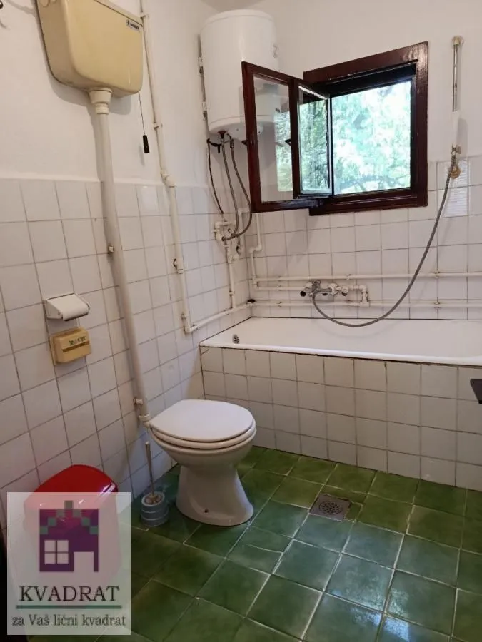 Starije kupatilo sa kadom, wc šoljom i bojlerom.