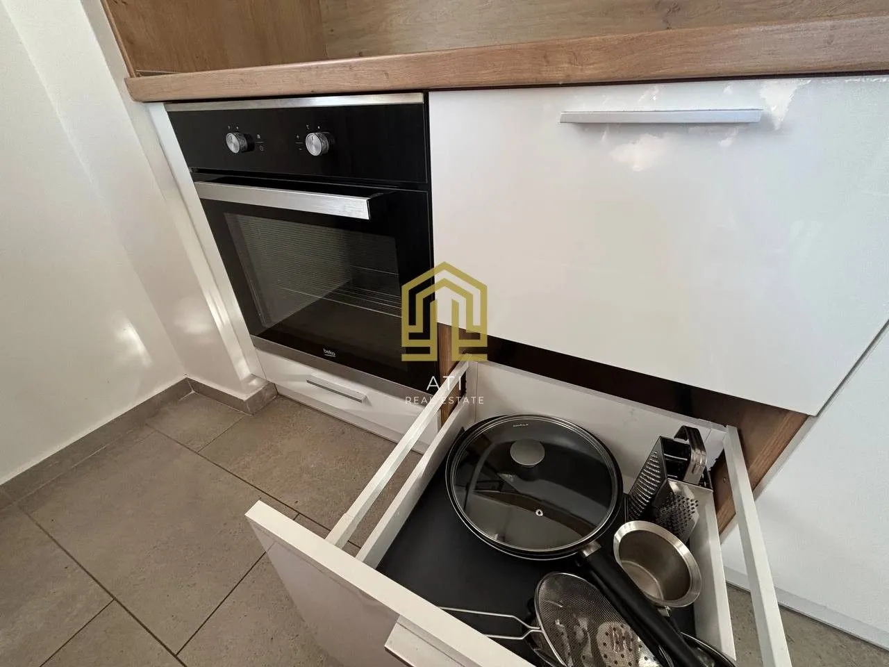 Modern kitchen with a built-in oven and an open drawer with cookware.