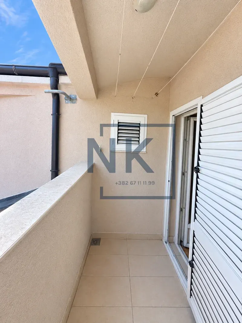 Small covered balcony with ceramic tiles and a door with shutters.