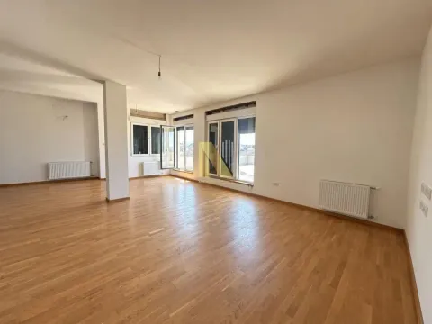 Prostrana prazna prostorija sa drvenim podom, belim zidovima i velikim prozorima koji vode na terasu. - image 3