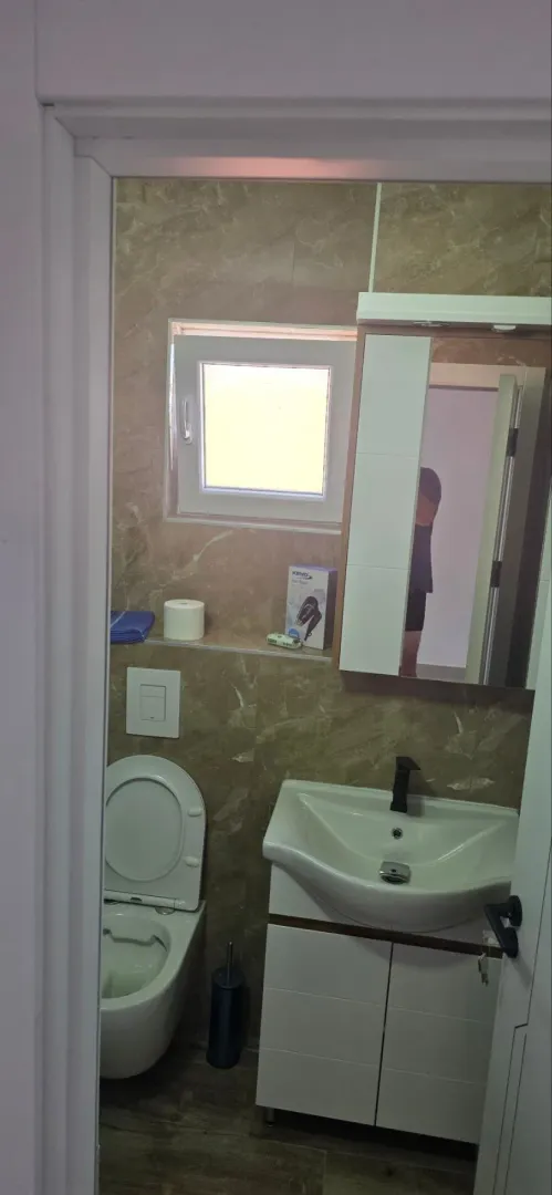 Pogled na kupatilo sa umivaonikom, WC šoljom i prozorom.