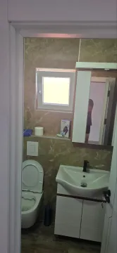 Pogled na kupatilo sa umivaonikom, WC šoljom i prozorom. - image 7
