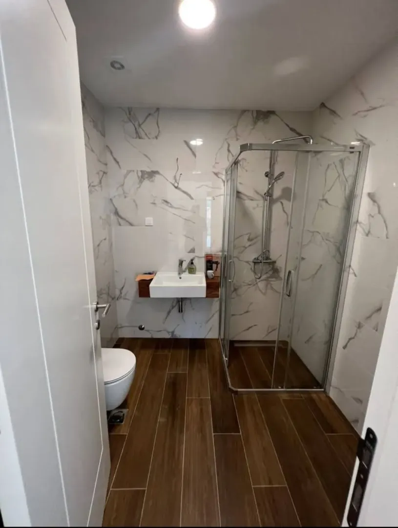 Moderne kupatilo sa tuš kabinom, umivaonikom i WC šoljom.