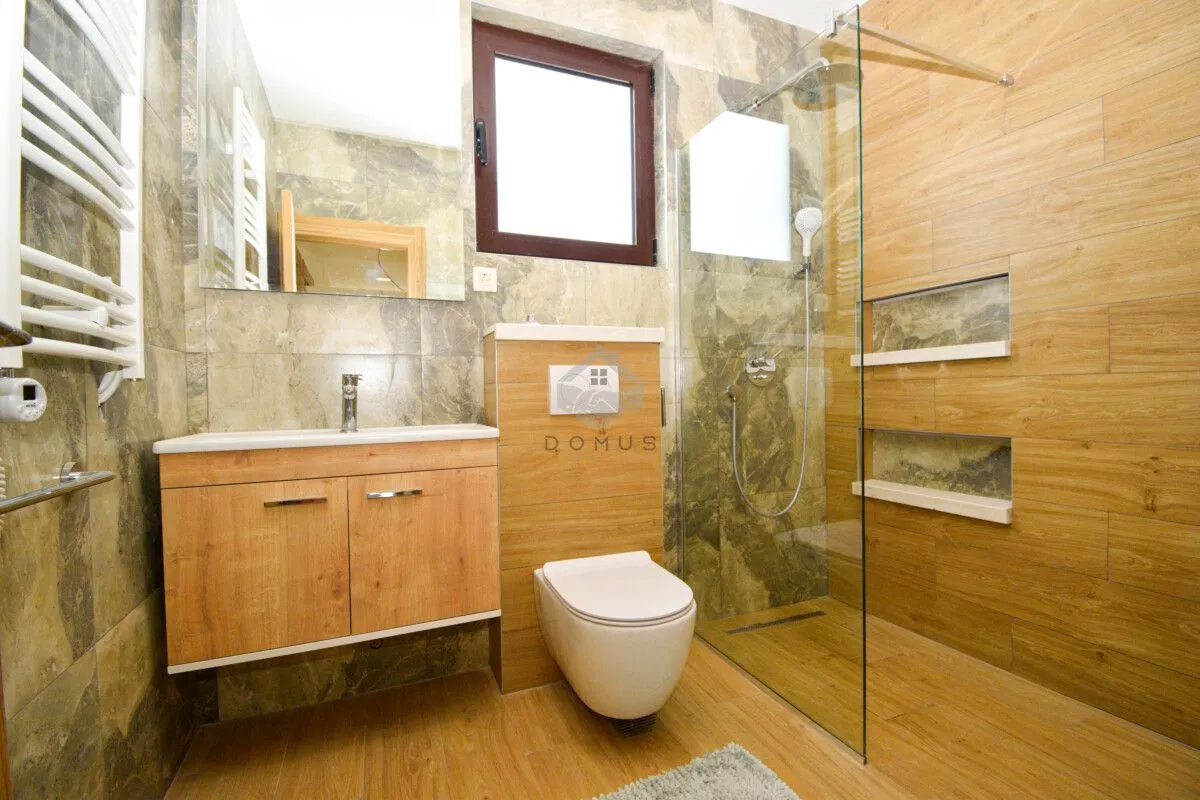 Modern bathroom with a walk-in shower, washbasin, and wall-hung toilet.