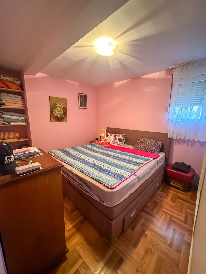 Namještena spavaća soba sa bračnim krevetom i roze zidovima.