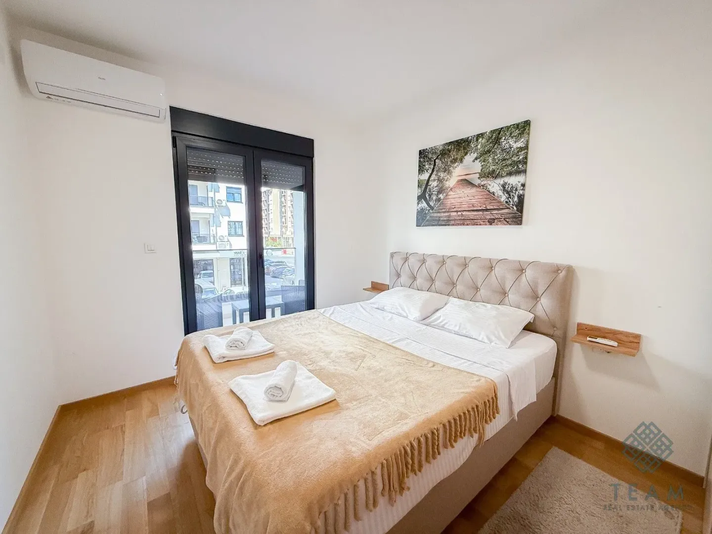Furnished bedroom with a double bed, air conditioning, and balcony doors.