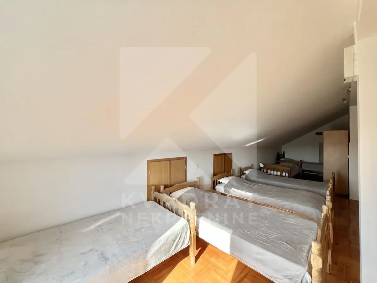 Attic bedroom with multiple wooden beds and parquet flooring.