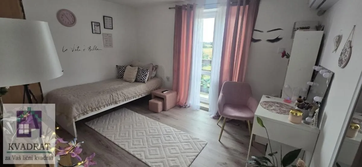 Nameštena spavaća soba sa krevetom, foteljom i radnim stočićem.
