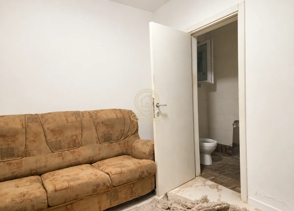 Dnevni boravak sa trosjedom i otvorenim vratima prema kupatilu.