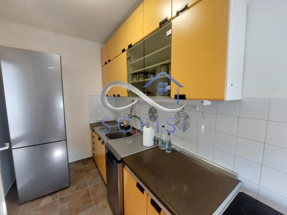 Manja kuhinja sa žutim elementima i ugradnim frižiderom.