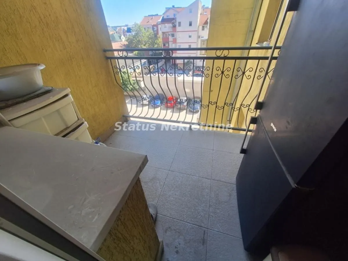 Manji natkriveni balkon sa metalnom ogradom i pogledom na naselje.