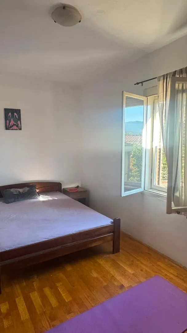 Spavaća soba sa bračnim krevetom i prozorom koji gleda spolja.
