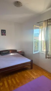 Spavaća soba sa bračnim krevetom i prozorom koji gleda spolja. - image 4