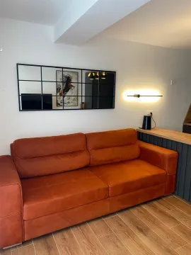 Living room with an orange sofa and a wall mirror. - image 7