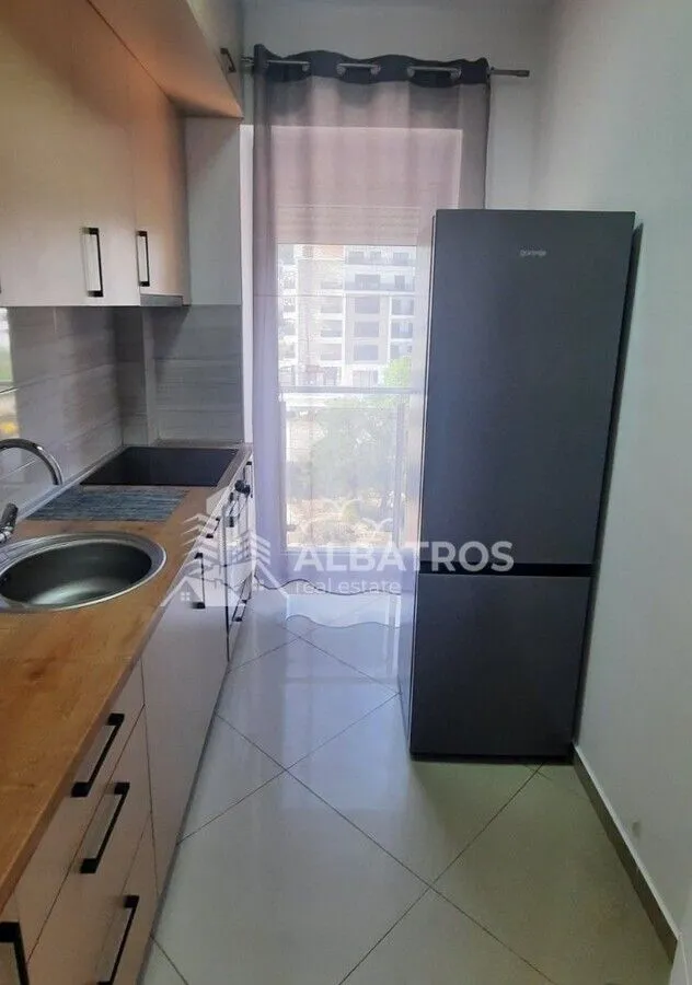 Small kitchen with wooden cabinets, refrigerator, and balcony access.