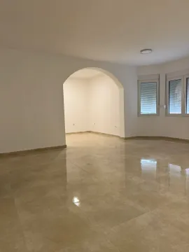 Spacious and bright empty room with tiled flooring and an arched doorway. - image 5
