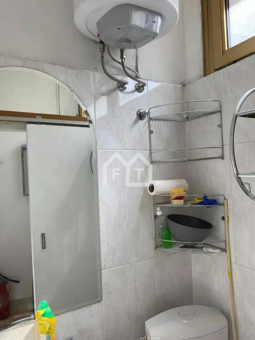 Small bathroom with tiled walls, water heater, and a mirror.