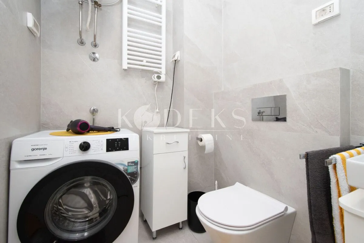 Modern bathroom with a washing machine, toilet, and sink.
