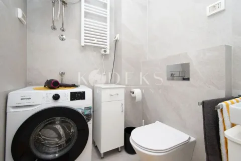 Modern bathroom with a washing machine, toilet, and sink. - image 7