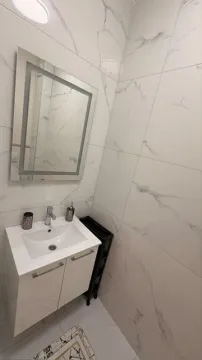 Small bathroom with a vanity, mirror, and white marble tiles. - image 14