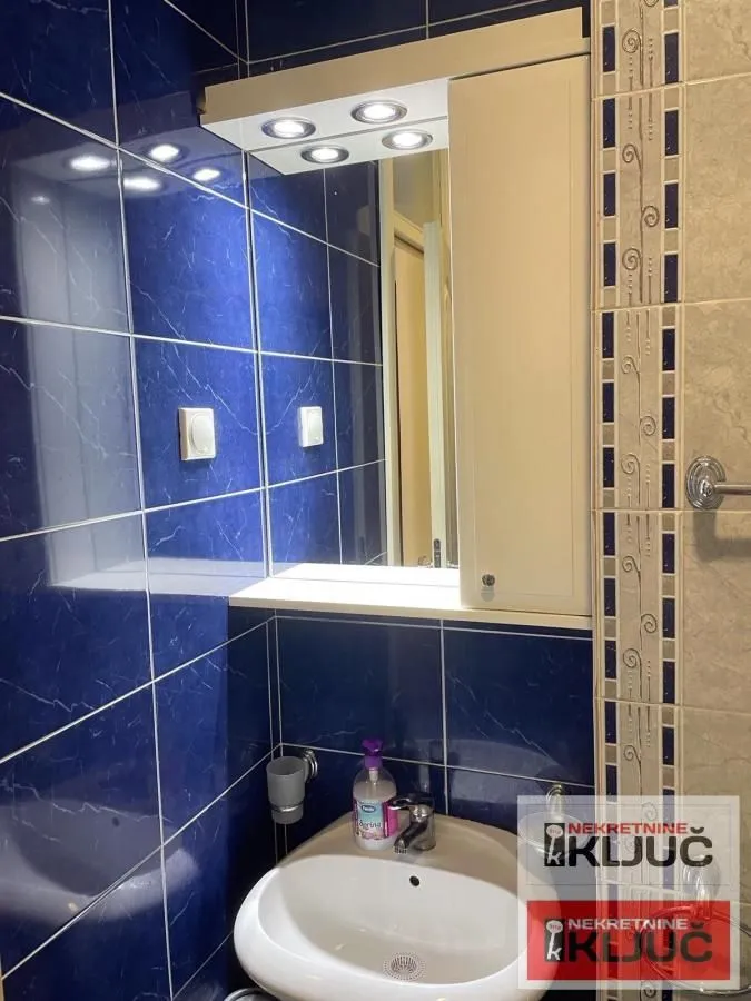 Bathroom with a washbasin, a mirror, and blue wall tiles.