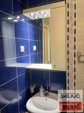 Bathroom with a washbasin, a mirror, and blue wall tiles. - image 4