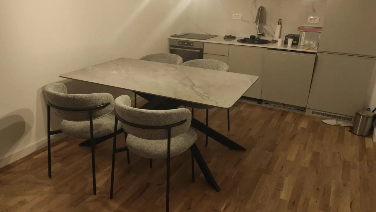 Manja kuhinja sa trpezarijskim stolom i sivim stolicama.