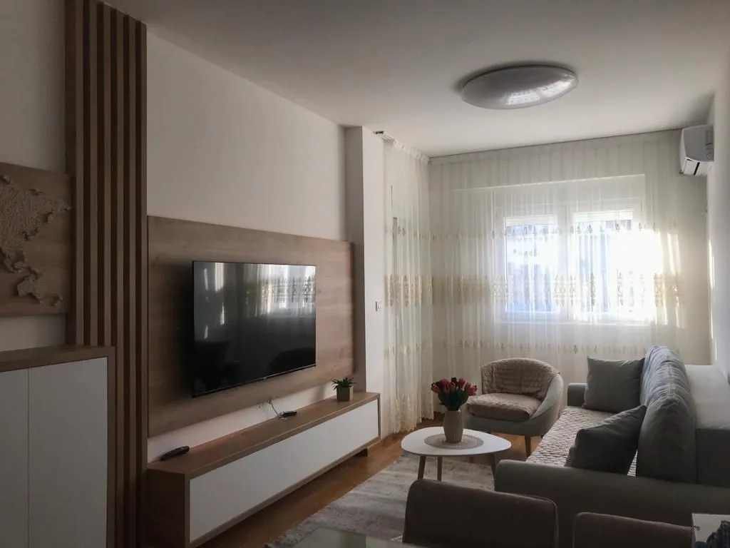 A bright living room with modern furniture and a wall-mounted TV.