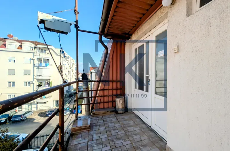 Manji popločani balkon sa metalnom ogradom i pogledom na ulicu.
