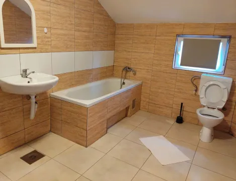 Small bathroom with a bathtub, washbasin, and toilet tiled with ceramic tiles. - image 7
