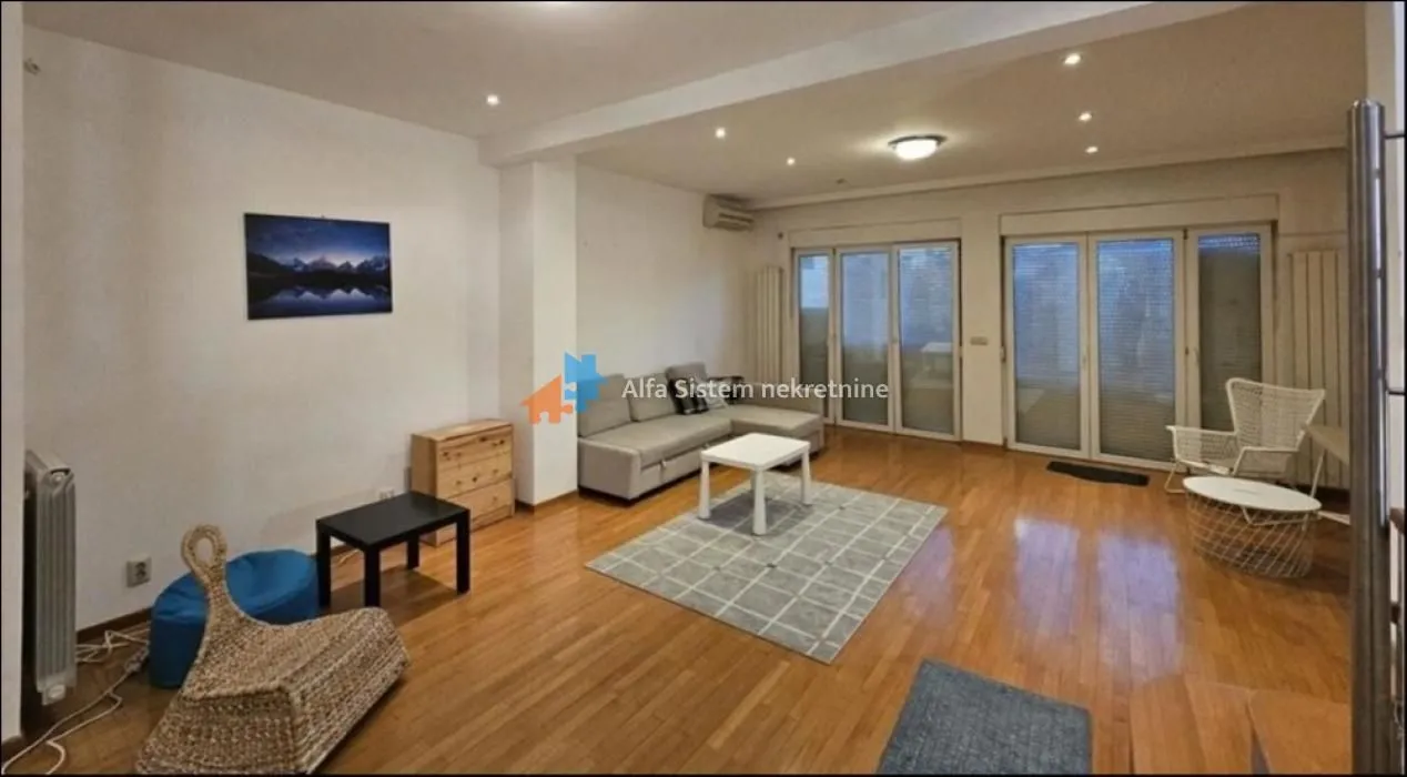 Spacious living room with a sofa set, hardwood flooring, and large glass doors leading outside.