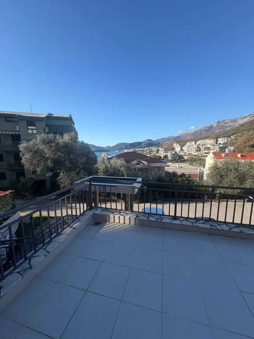 Prostrana popločana terasa sa metalnom ogradom i pogledom na more i okolinu.