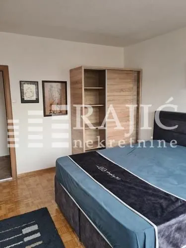 Furnished bedroom with a double bed and a wooden wardrobe.