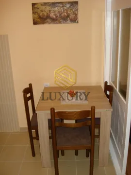 Small dining area with a wooden table and four chairs. - image 5