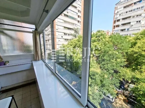 Zastakljena terasa sa pogledom na gradsko zelenilo i zgrade. - image 14