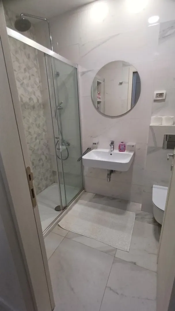 Modern bathroom with a shower cabin, washbasin, and toilet.