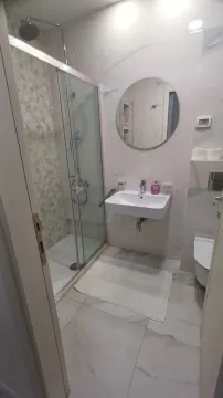Modern bathroom with a shower cabin, washbasin, and toilet. - image 6
