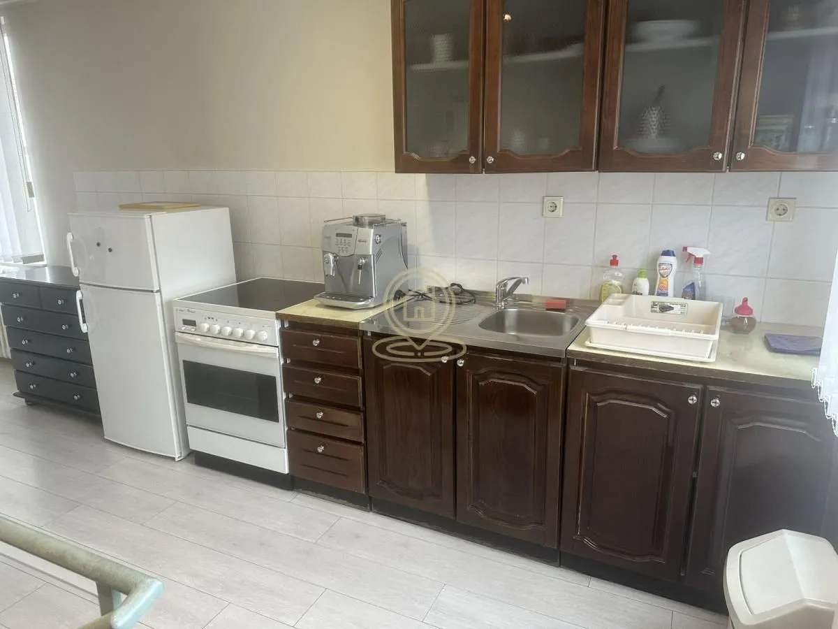 Kitchen with dark wooden cabinets, white appliances, and a sink.