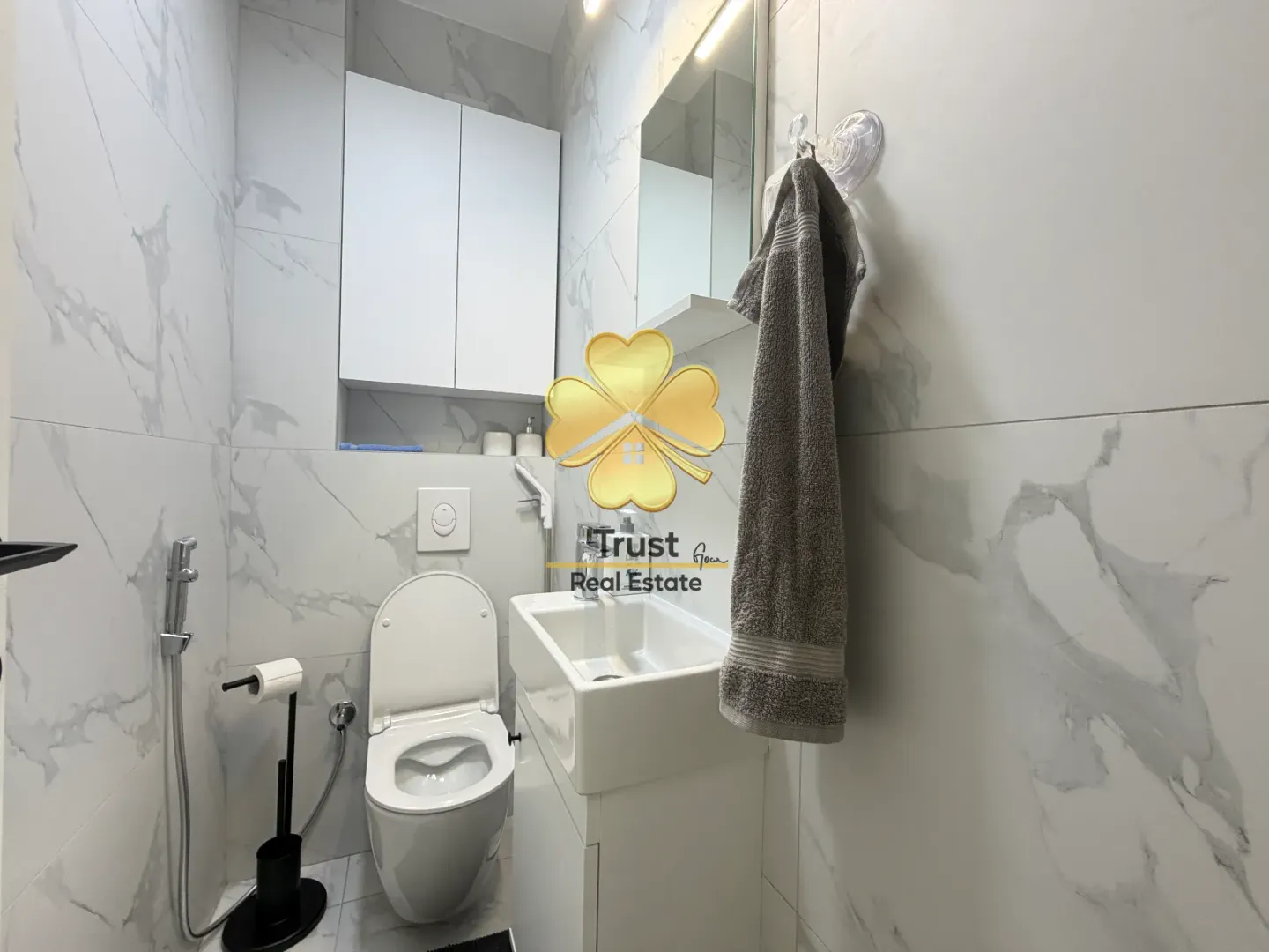 Moderno opremljeno kupatilo sa bijelim keramičkim pločicama i sanitarijama.