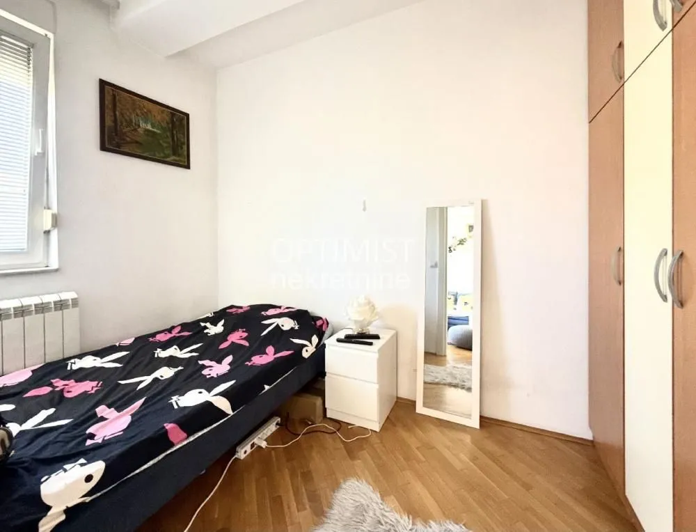 Manja spavaća soba sa krevetom, garderoberom i prozorom.