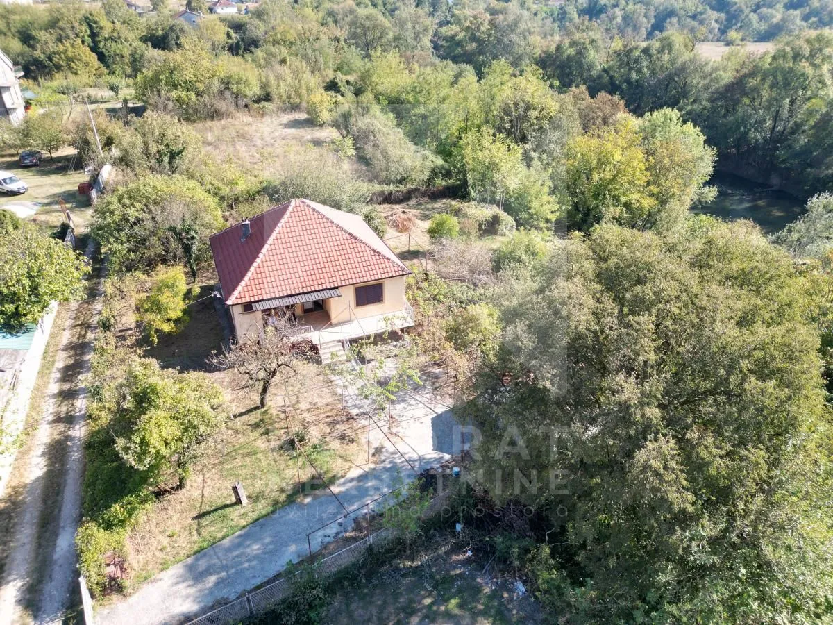 Pogled iz vazduha na kuću sa dvorištem okruženom zelenilom.