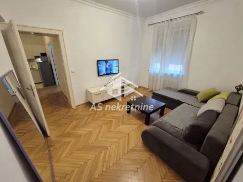 Living room with a sofa, TV, and wooden parquet flooring. - image 2
