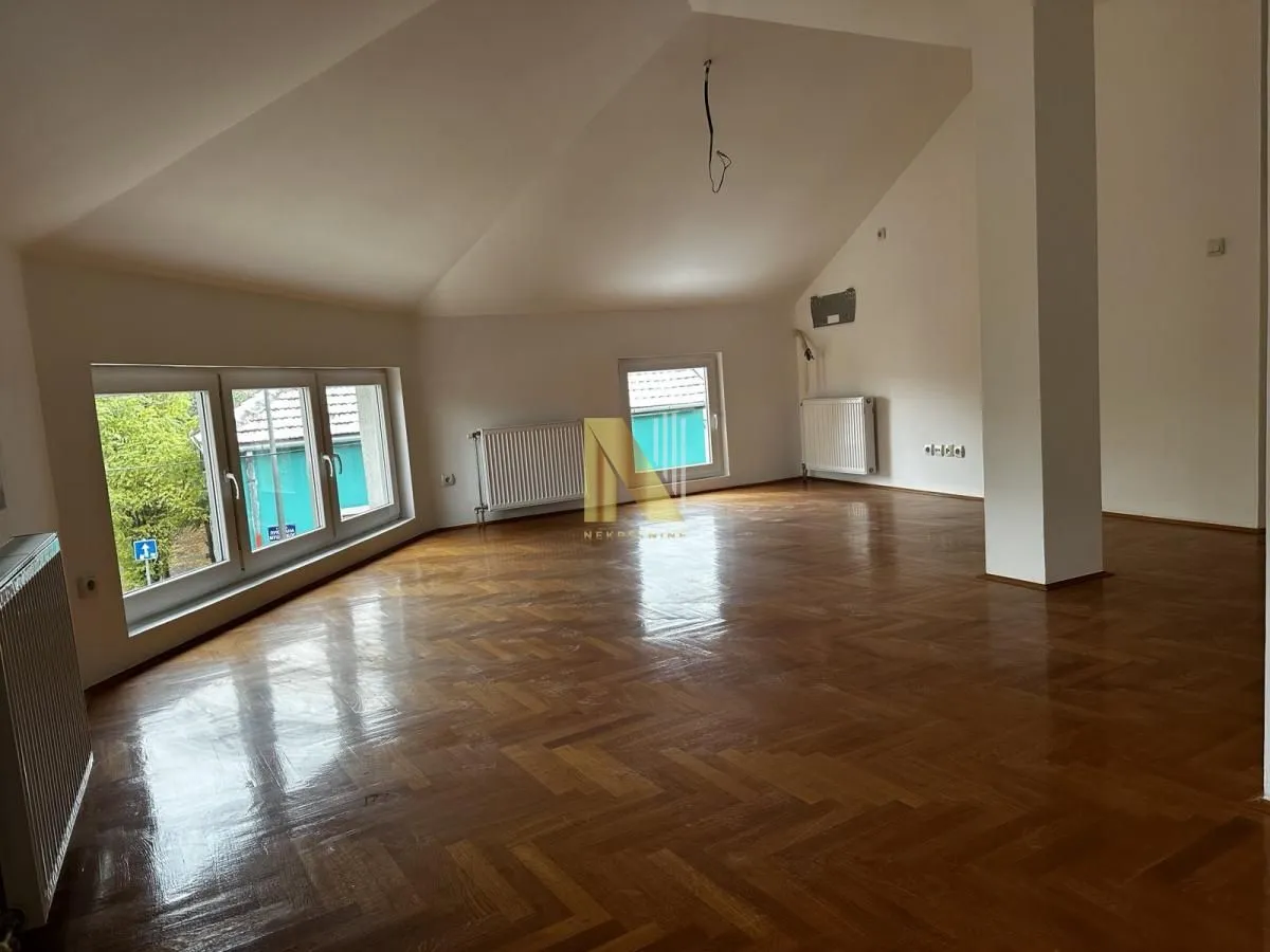 Spacious empty room with parquet flooring and a sloped ceiling.