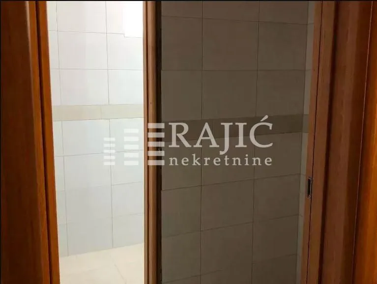 View of a tiled bathroom through an open door.