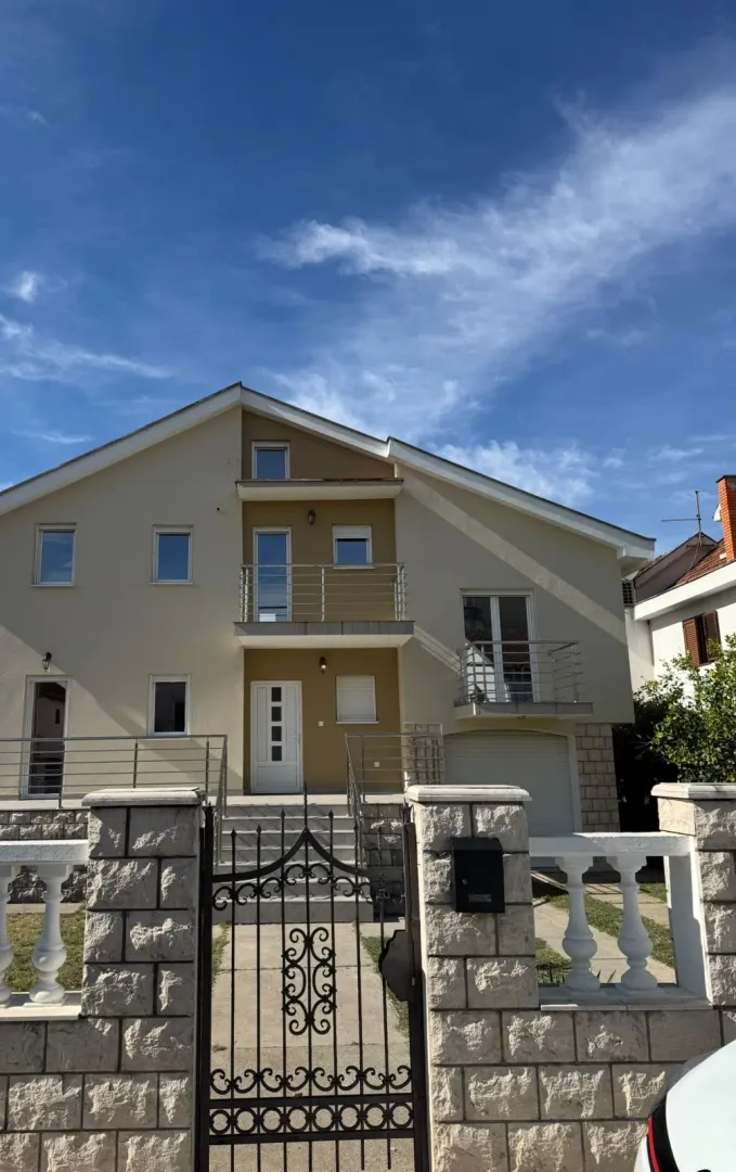 Front view of a two-story house with a yard gate and balcony.