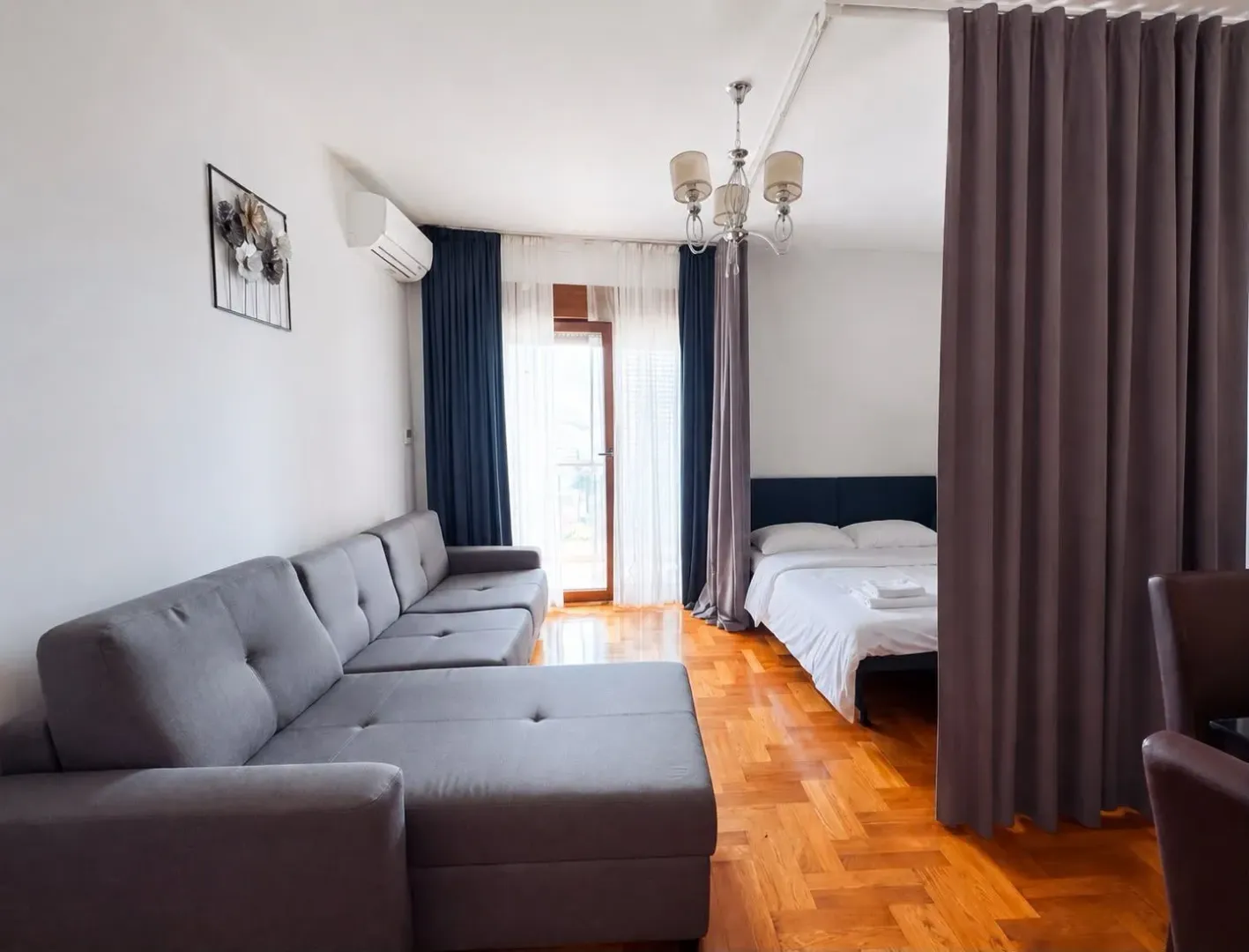 Dnevni boravak sa garniturom za sjedenje i krevetom odvojenim zavjesom.