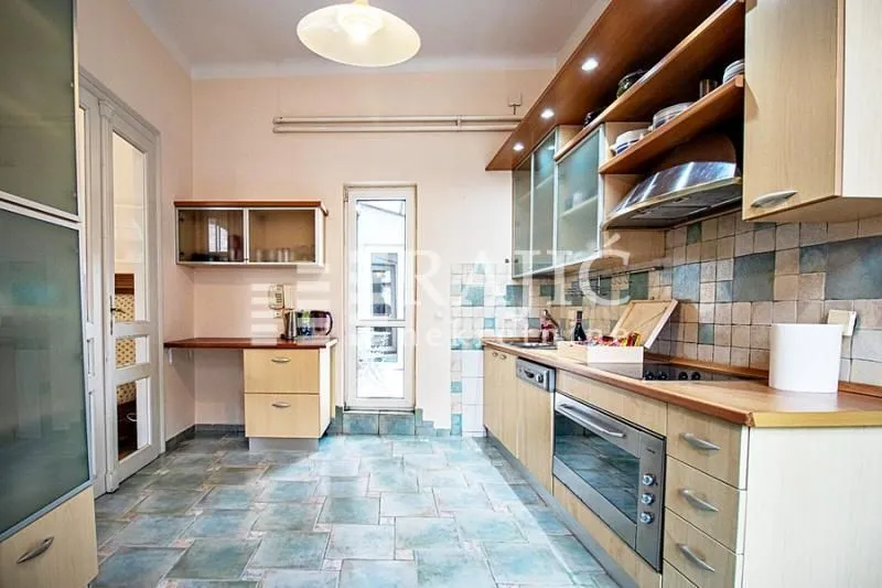Spacious kitchen with wooden cabinets and tiled flooring.